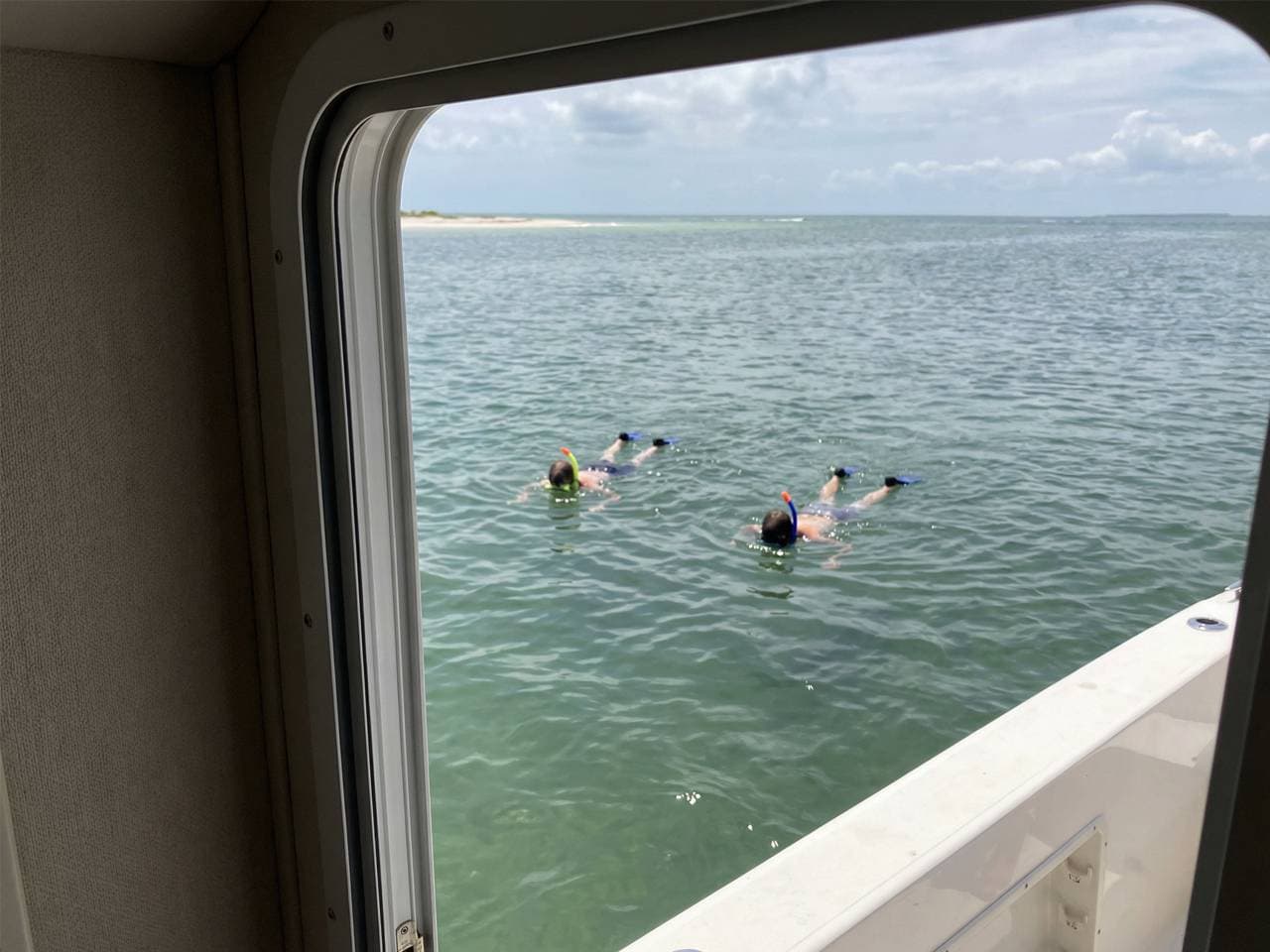 Two snorkelers seen through the boat cabin window